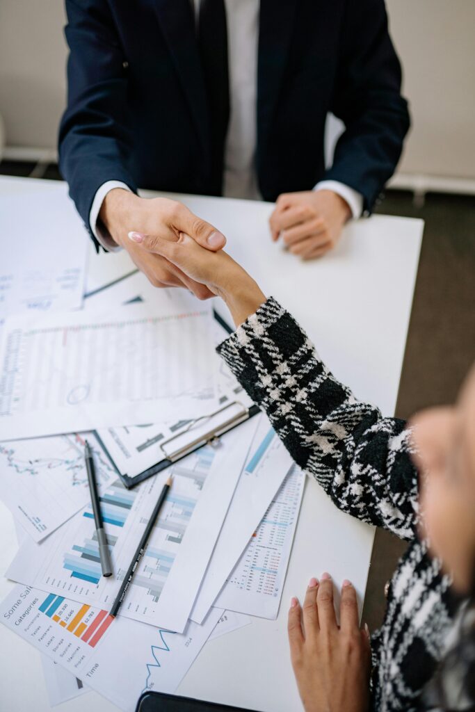 Executive Outplacement A close-up photo of a business handshake over financial documents in an office environment.