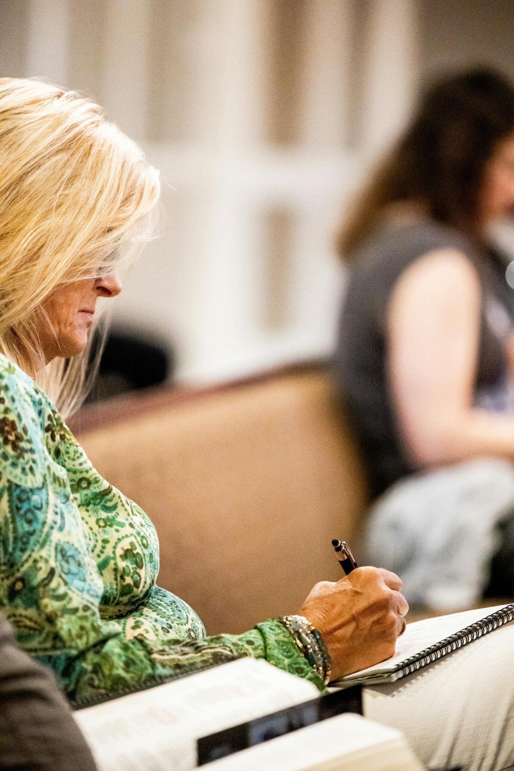 Formación y Seminarios A woman attentively taking notes during a class, emphasizing focus and concentration.